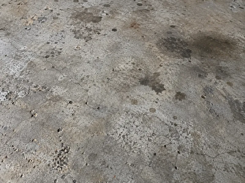 Stained, pitted concrete garage floor before resurfacing